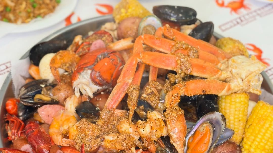 A seafood boil tray of snow crab legs, lobster tail, crawfish, shrimp, mussels and corn at Rusty Crab Daddy
